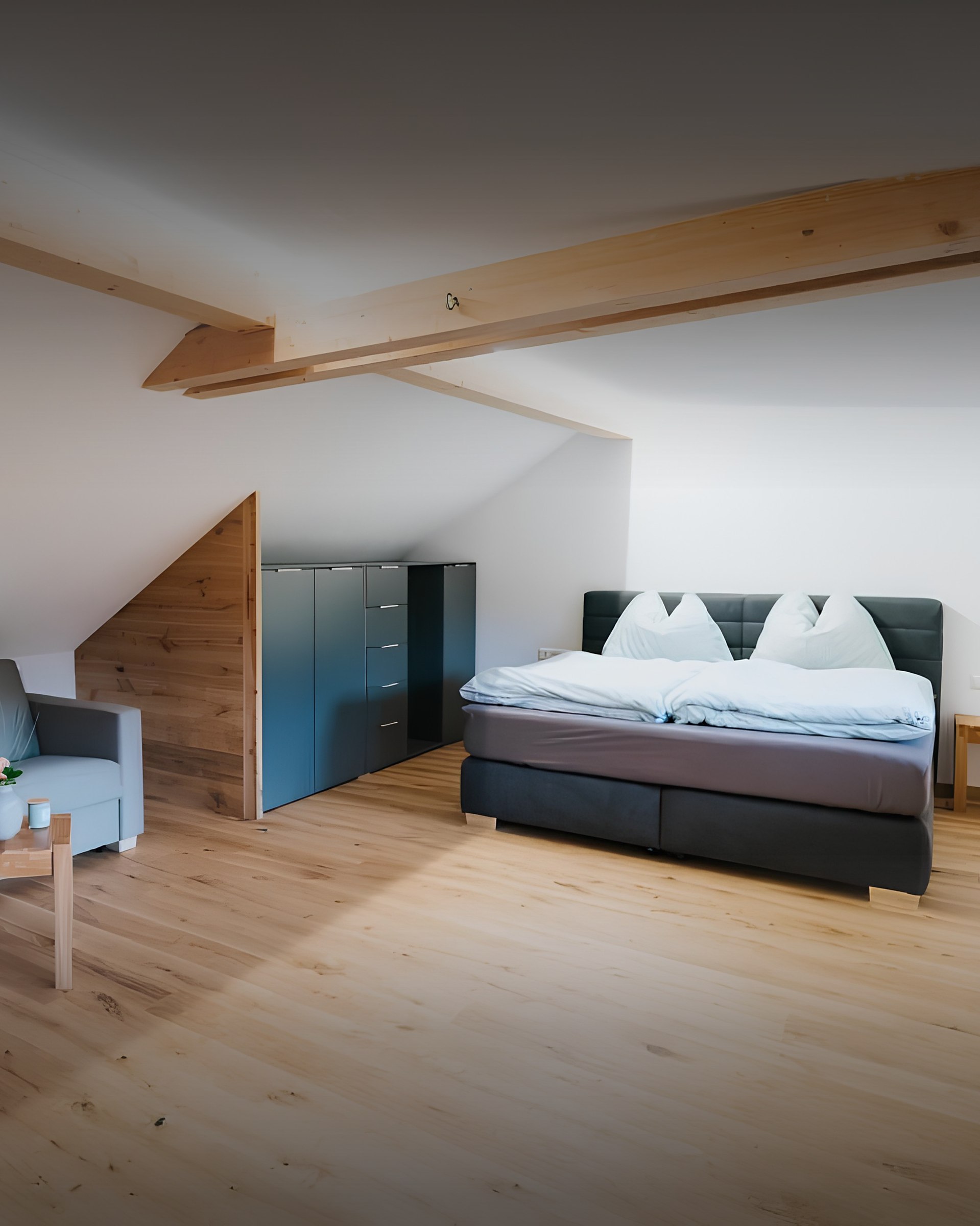 Helles Dachgeschoss-Schlafzimmer mit Boxspringbett und Holzbalken im Ferienhaus Gnesau