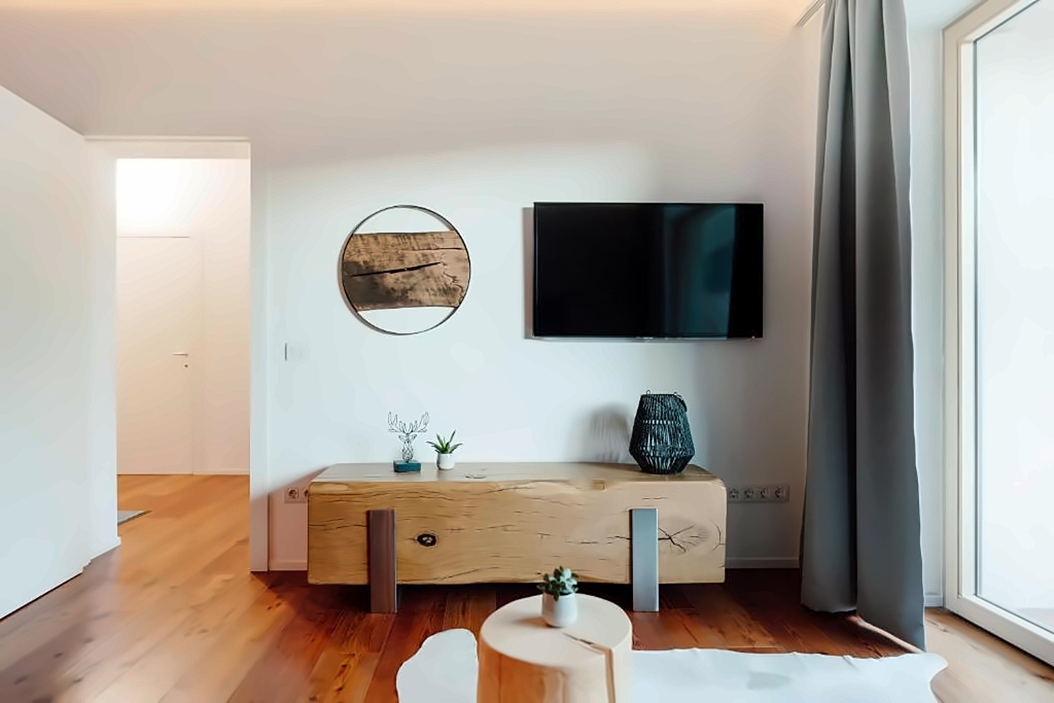 Modernes Wohnzimmer mit Smart-TV und bodentiefem Fenster